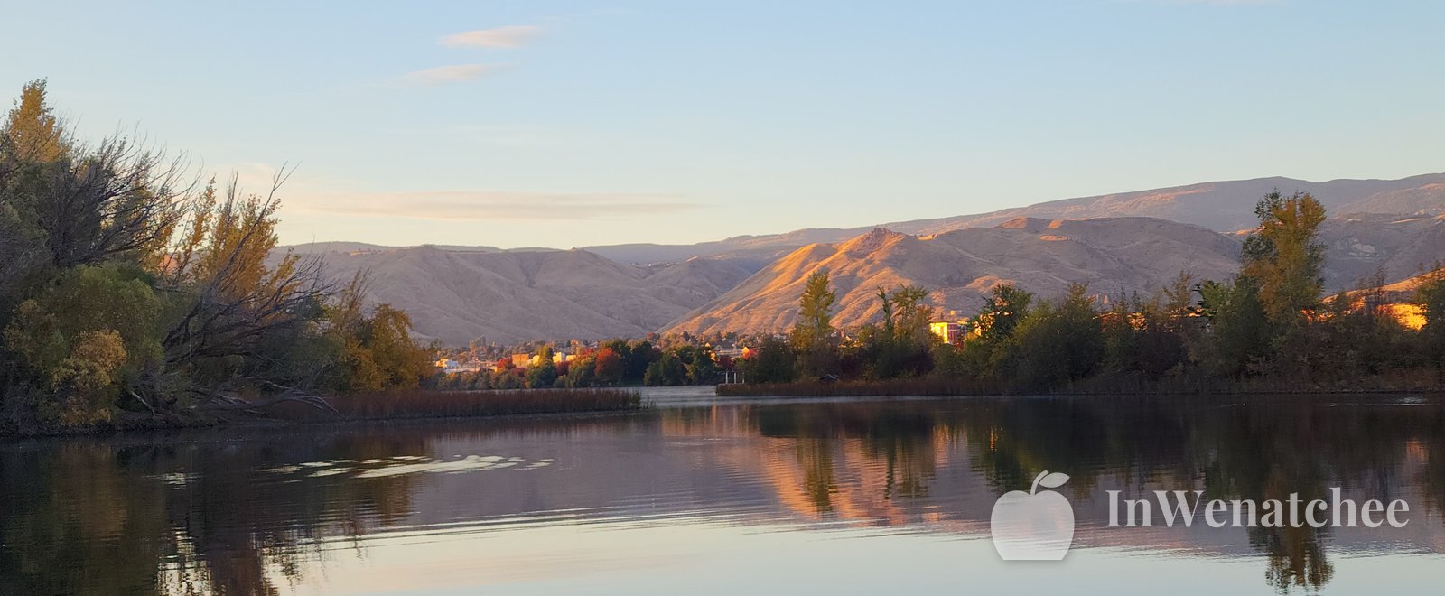 Dusk view of the Columbia from the Wenatchee riverfront, with silhouetted hills, still water, and reeds in the foreground.