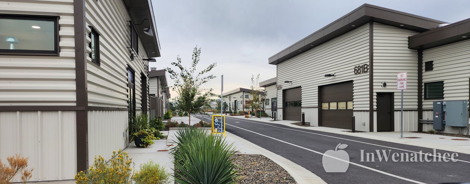 Street between modern industrial-style buildings with garage doors, with an agave plant in the foreground.